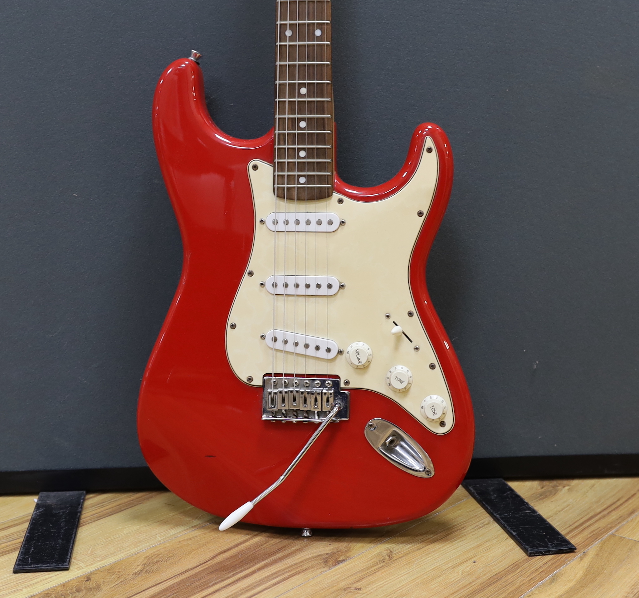 A Squier Strat by Fender electric guitar with rosewood neck and red lacquer body